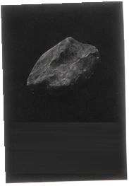 A small rock photographed against the dark surface of a notebook.